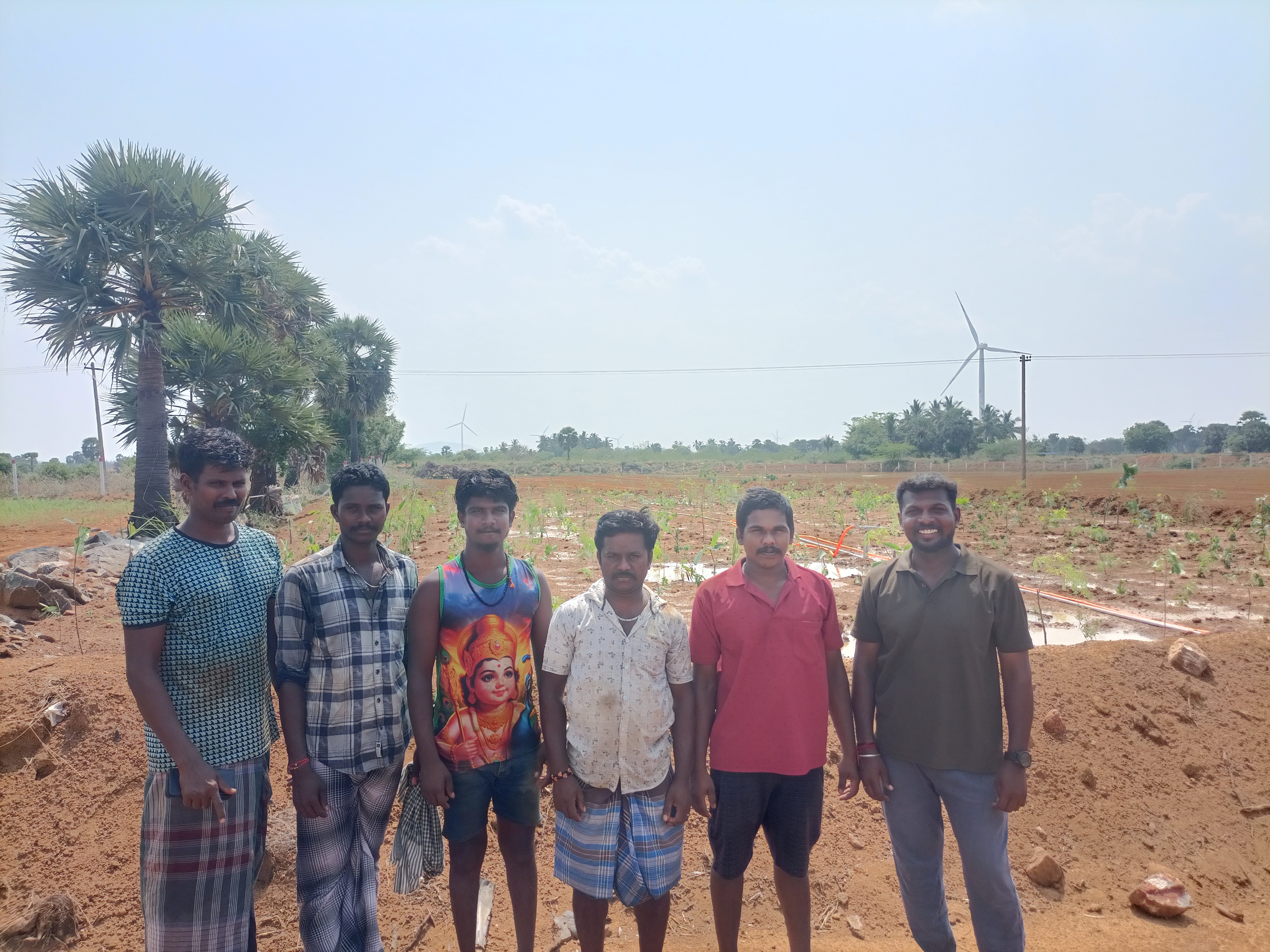 Members of the farm team standing together in front of newly planted saplings